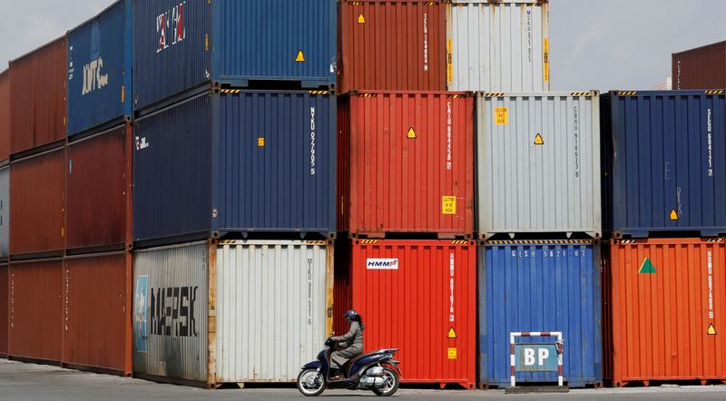 FILE PHOTO: A woman rides a motorcycle as she passes containers at Hai Phong port, Vietnam September 25, 2018. Picture taken September 25, 2018. REUTERS/Kham/File Photo