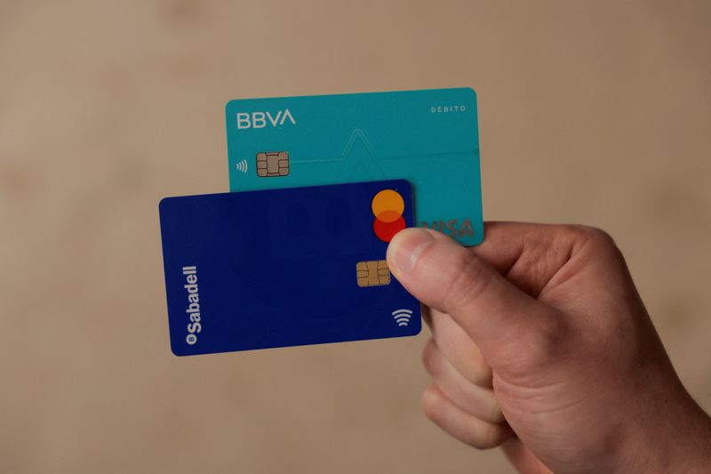 FILE PHOTO: A man shows his debit cards of BBVA and Sabadell banks, in Ronda, Spain, May 9, 2024. REUTERS/Jon Nazca/File Photo