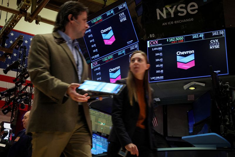 FILE PHOTO: Traders work on the floor as screens display the logo for Chevron Corp. at the New York Stock Exchange (NYSE) in New York City, U.S., October 23, 2023.  REUTERS/Brendan McDermid/File Photo