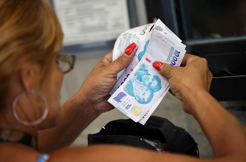 A customer counts Argentine peso bills before checking out in a supermarket, in Buenos Aires, Argentina January 13, 2025. REUTERS/Agustin Marcarian