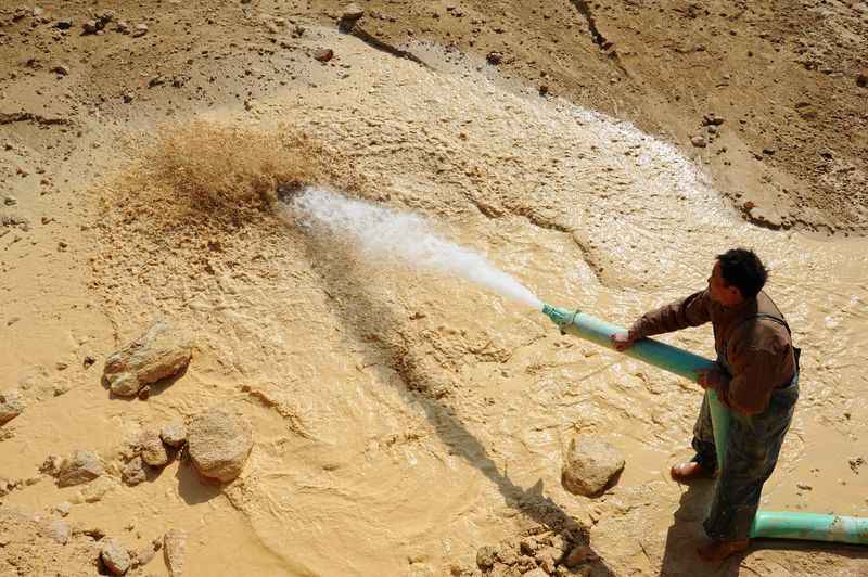 FILE PHOTO: A worker waters the site of a rare earth metals mine at Nancheng county, Jiangxi province January 16, 2011. REUTERS/Stringer/File Photo