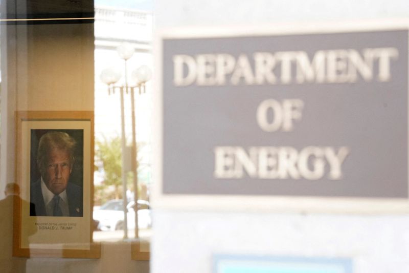 FILE PHOTO: A person reflects in the window of the U.S. Department of Energy, with the official portrait of U.S. President Donald Trump on the wall, following a partial government shutdown in Washington, D.C., U.S., October 2, 2025. REUTERS/Nathan Howard/File Photo
