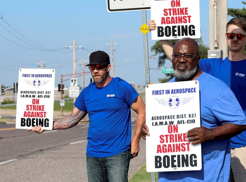 FILE PHOTO: Workers hold signs during a walkout by members of the International Association of Machinists and Aerospace Workers (IAM) over contract negotiations, outside Boeing company's facility, in Berkeley, Missouri, U.S., August 4, 2025. REUTERS/Lawrence Bryant/File Photo