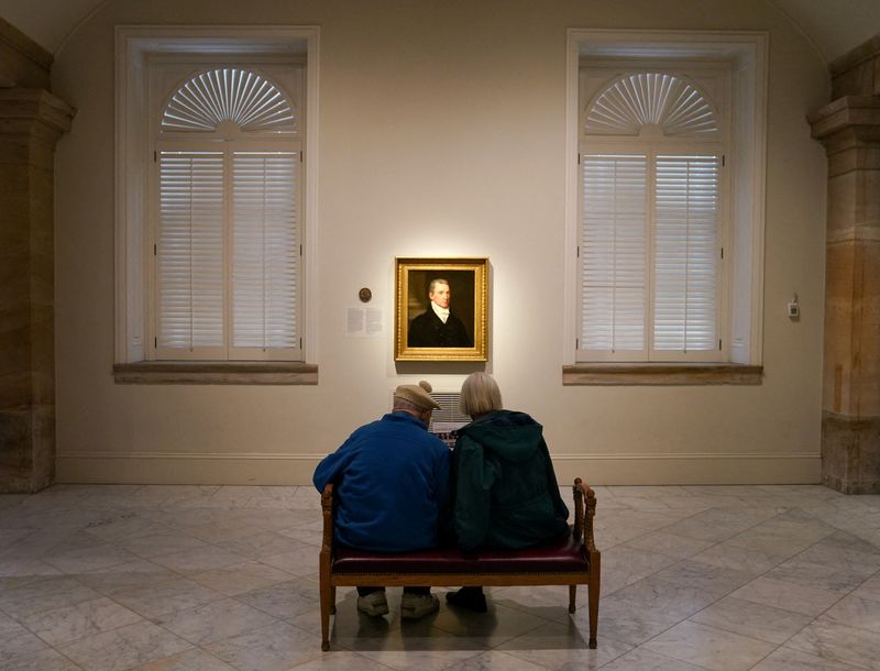 FILE PHOTO: Seated in front of a portrait of President James Monroe, a couple looks at a guide to the "Americas' Presidents" exhibition at the National Portrait Gallery in Washington, U.S., February 13, 2023. REUTERS/Kevin Lamarque/File Photo