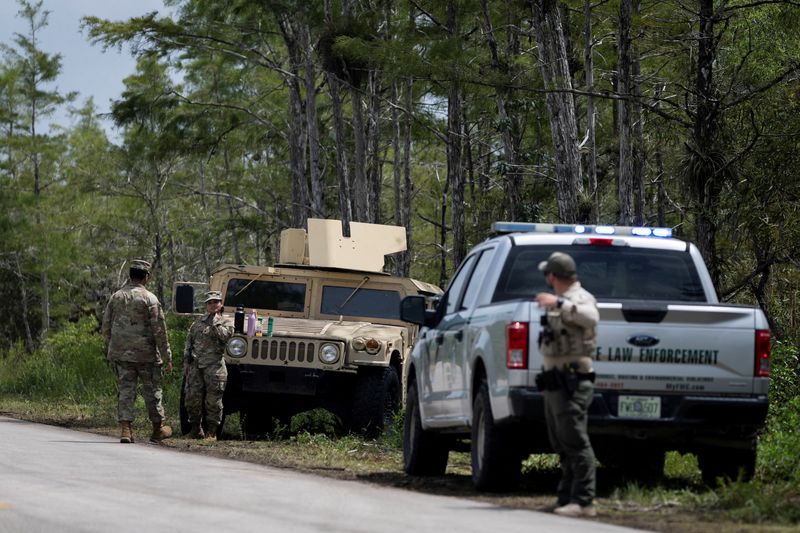 FILE PHOTO: Florida's National Guard members stand at the entrance of the Dade-Collier Training and Transition Airport as people rally against the state's forthcoming "Alligator Alcatraz" ICE detention center in Ochopee, Florida, U.S. June 28, 2025. REUTERS/Marco Bello/File Photo