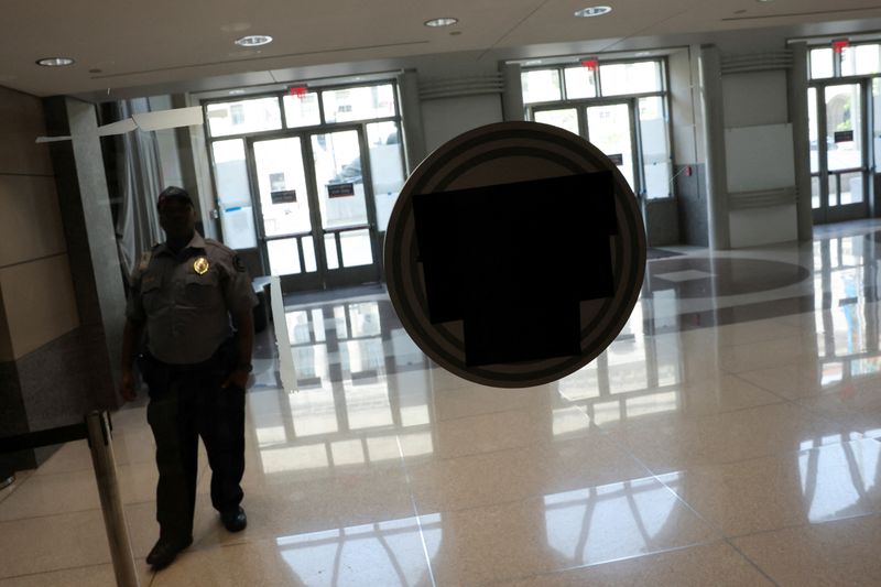 FILE PHOTO: A security guard is stationed in the former offices of the U.S. Agency for International Development (USAID), where black tape covers the signage on the windows, in the Ronald Reagan Building and International Trade Center in Washington, D.C., U.S., April 24, 2025. REUTERS/Jonathan Ernst/File Photo