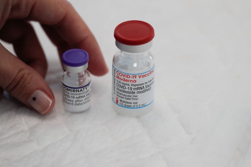 FILE PHOTO: A healthcare worker places vials containing doses of the "Comirnaty" Pfizer BioNTech and Moderna vaccines against the coronavirus disease (COVID-19) on a table at a vaccination centre in Ronda, Spain November 10, 2021. REUTERS/Jon Nazca/File Photo