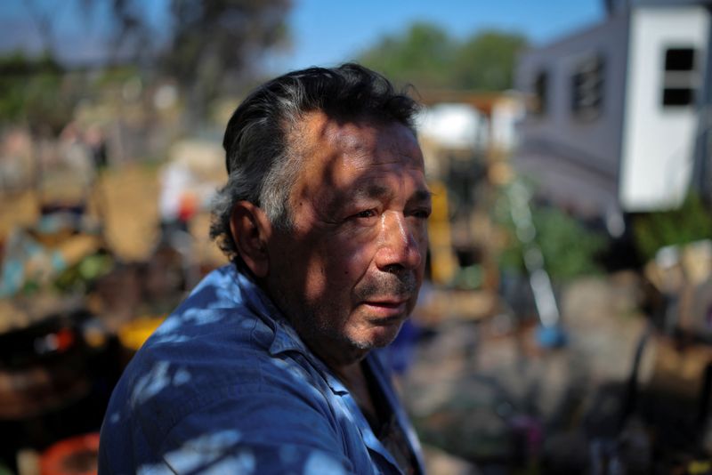 Jose Luis Martinez, 71, stands in the front yard where his home used to be after he lost it to the Eaton Fire in January 2025 and where he now lives in an RV, in Altadena, California, U.S., June 27, 2025. While many homeowners complain about delays, L.A. city and county officials say rebuilding progress has exceeded initial expectations. About 75% of the 4,398 residential lots destroyed or severely damaged in the city of Los Angeles have been cleared of debris and are certified for rebuilding. "I don't have a million dollars, I would have to ask for a loan, and I don’t have 30 years of life left to pay off a loan like that," said Martinez, who had been in his home 38 years when it burned down, was uninsured and living on Social Security. REUTERS/Daniel Cole