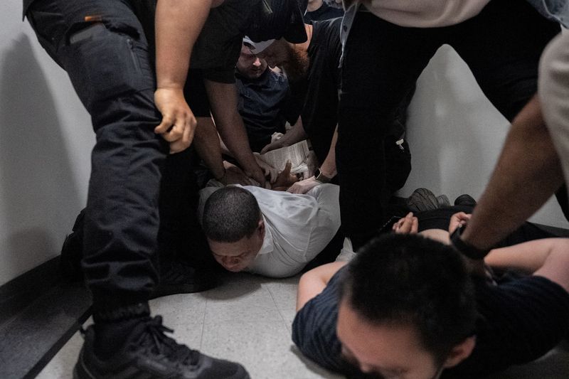 FILE PHOTO: A migrant is detained by federal immigration officers at U.S. immigration court in Manhattan, in New York City, U.S., June 6, 2025. REUTERS/David 'Dee' Delgado/File Photo