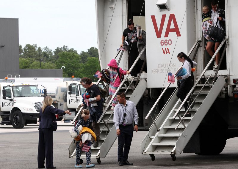 The first group of white South African refugees step from a "people mover" upon arrival at Dulles International Airport in Dulles, Virginia, U.S., May 12, 2025. REUTERS/Kevin Lamarque/File Photo