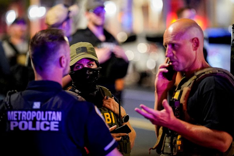 FILE PHOTO: Members of the Federal Bureau of Investigation (FBI) confer with a Metropolitan Police Department office during a traffic stop, after U.S. President Donald Trump deployed National Guard and ordered an increased presence of federal law enforcement to assist in crime prevention, in Washington, D.C., U.S., August 17, 2025. REUTERS/Al Drago/File Photo