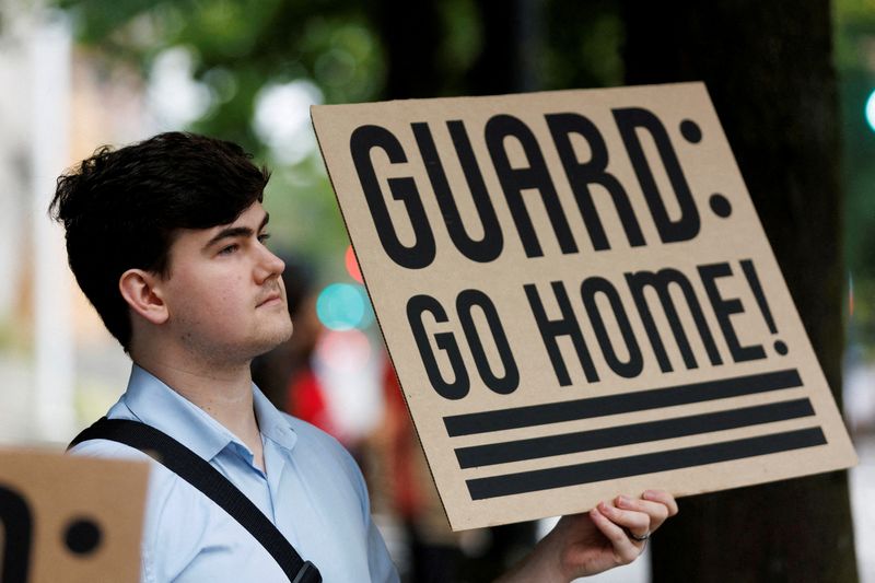 FILE PHOTO: A protestor holds a sign at a rally at Mark O. Hatfield Federal Courthouse, as protestors anticipate a ruling by Federal District Court Judge Karin Immergut regarding President Donald Trump's plan to deploy National Guard members in Portland, in Portland, Oregon, U.S., October 3, 2025. REUTERS/John Rudoff/File Photo