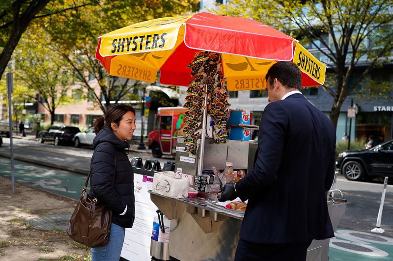 A customer buys lunch from furloughed federal worker Issac Stein, 31, at his hot dog stand weeks into the continuing U.S. government shutdown, in Washington, D.C., U.S., October 24, 2025. REUTERS/Elizabeth Frantz