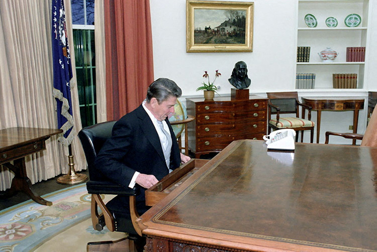 FILE PHOTO: Ronald Reagan sits at the Oval Office desk following his inaugural parade in Washington, D.C., U.S. in January 1981.Ronald Reagan Presidential Library/Handout via REUTERS