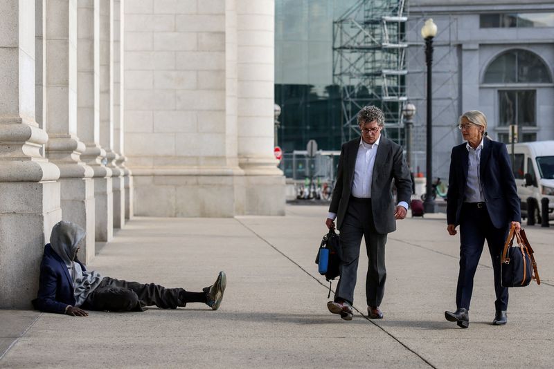 People walk by a homeless person outside Union Station in Washington, D.C., U.S., October 27, 2025. REUTERS/Kylie Cooper