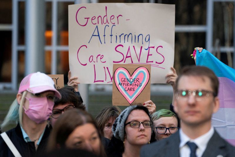 FILE PHOTO: People hold pro-trans signs after a hearing in the multi-state lawsuit over President Trump's order ending all federal funding or support for healthcare that aids gender transitions for people younger than 19, outside a courthouse in Seattle, Washington, U.S., February 28, 2025.    REUTERS/David Ryder/File Photo