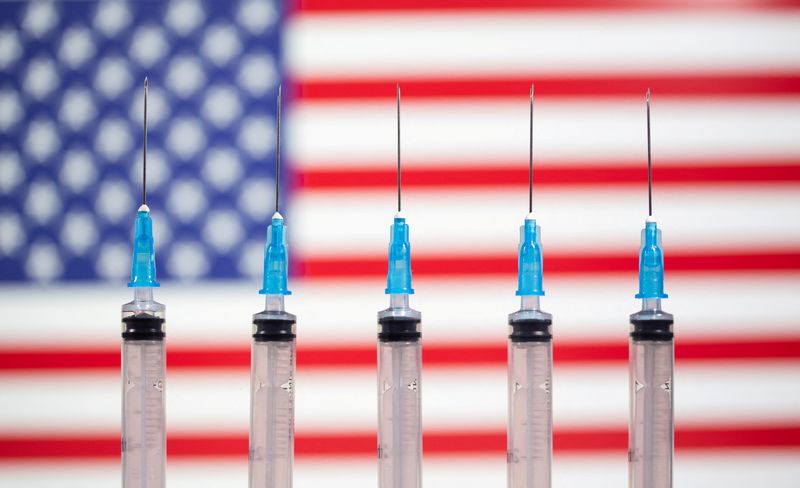 FILE PHOTO: Syringes are seen in front of a displayed U.S. flag in this illustration taken November 10, 2020. REUTERS/Dado Ruvic/Illustration/File Photo