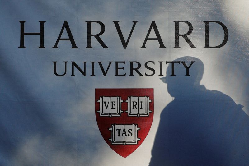 FILE PHOTO: A pedestrian casts a shadow on a Harvard University sign after U.S. President Donald Trump said that his administration was close to a deal with Harvard University, in Cambridge, Massachusetts, U.S., September 30, 2025.   REUTERS/Brian Snyder/File Photo
