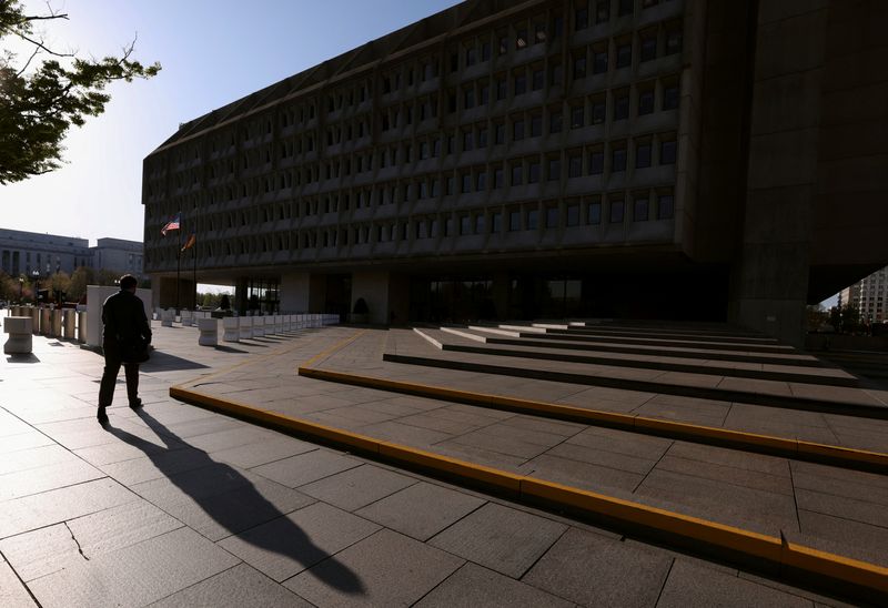 A man casts a shadow as he walks toward the Hubert H. Humphrey Building, headquarters of the  Department of Health and Human Services (HHS), in Washington, D.C., U.S., April 1, 2025. REUTERS/Kevin Lamarque