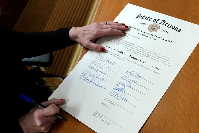FILE PHOTO: A member of Arizona's Electoral College signs the Arizona Presidential Elector Ballot certificate in Phoenix, Arizona, U.S. December 14, 2020. Ross D. Franklin/Pool via REUTERS/File Photo