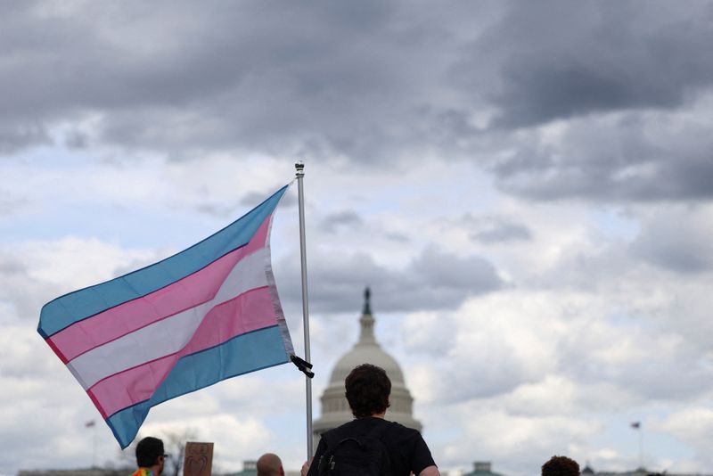 FILE PHOTO: A person holds a flag as the Capitol is seen in the background during a Transgender Day of Visibility rally on the National Mall in Washington, D.C., U.S., March 31, 2025. REUTERS/Evelyn Hockstein/File Photo