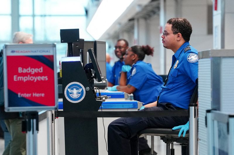 FILE PHOTO: TSA agents work at a security checkpoint at Ronald Reagan International Airport in Arlington, Virginia., U.S., March 15, 2026. REUTERS/Aaron Schwartz/File Photo