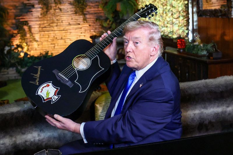 U.S. President Donald Trump holds a replica of a guitar after signing it during a visit to Graceland, the home of Elvis Presley, in Memphis, Tennessee, U.S., March 23, 2026. REUTERS/Kevin Lamarque