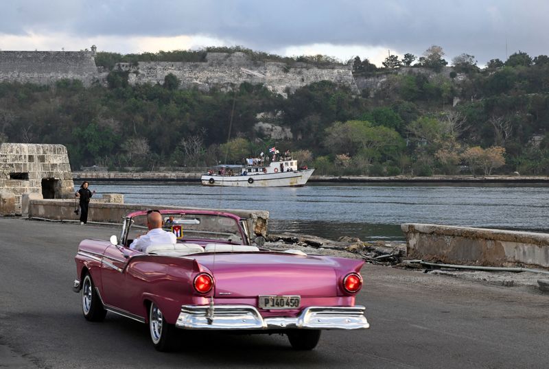 Activists wave flags as they arrive on a boat carrying a shipment of humanitarian aid from the Nuestra America Convoy, an international effort organized by global activists seeking to circumvent U.S. sanctions that severely restrict shipments of fuel and other goods to the island, in Havana, Cuba, March 24, 2026. REUTERS/Norlys Perez