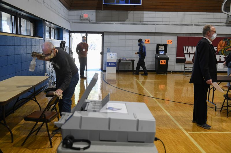 A poll worker disinfects the polling area at Van Cleve Park Recreation on election day in Minneapolis, Minnesota U.S. November 3, 2020.  REUTERS/Nicholas Pfosi