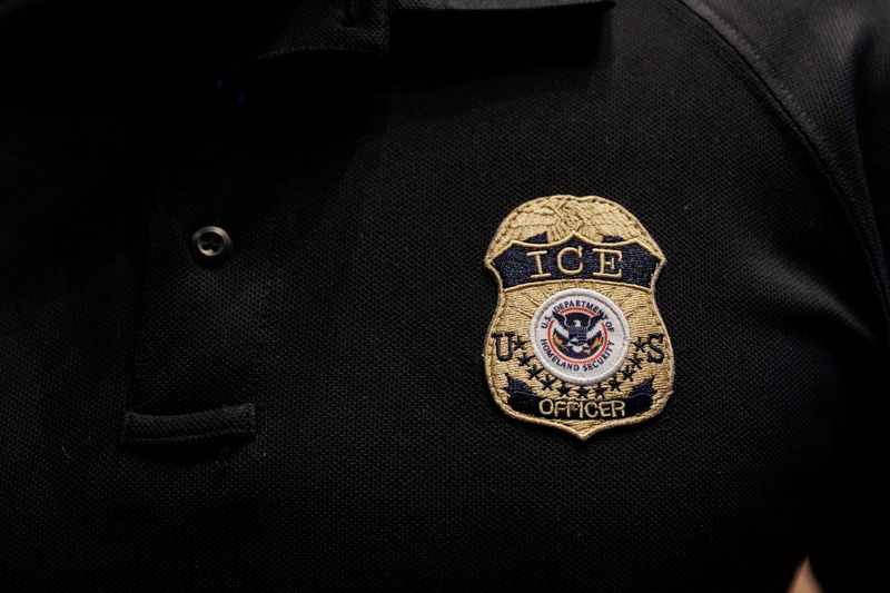 FILE PHOTO: The badge of a U.S. Immigration and Customs Enforcement (ICE) is embroidered on a polo shirt of an ICE employee, at a U.S. Immigration and Customs Enforcement  two-day job fair in Texas to help fill vacancies for deportation officers and attorneys, in Arlington, Texas, U.S. August 26, 2025.  REUTERS/Shelby Tauber/File Photo