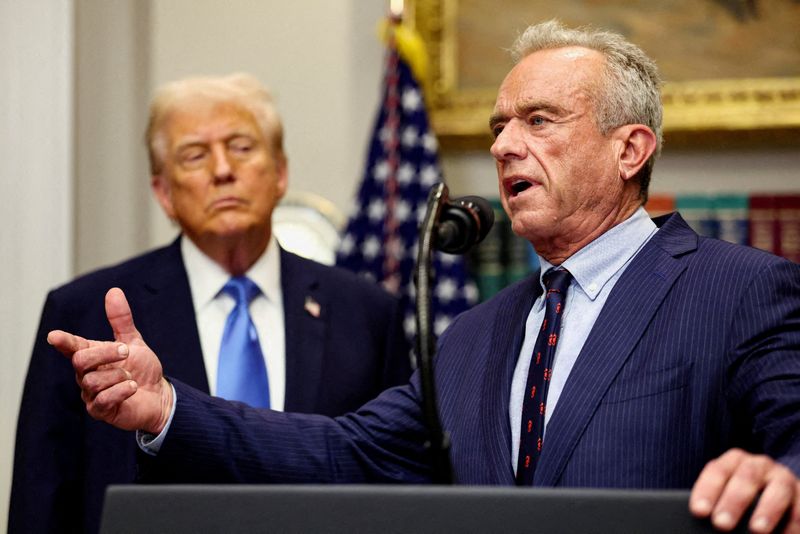 FILE PHOTO: U.S. Secretary of Health and Human Services Robert F. Kennedy Jr. delivers remarks while U.S. President Donald Trump listens during a press conference to announce a link between autism and childhood vaccines and the use of popular pain medication Tylenol for pregnant women and children, claims which are not backed by decades of science, at the White House in Washington, D.C., U.S., September 22, 2025. REUTERS/Kevin Lamarque/File Photo