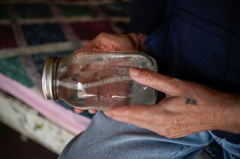 Hanson Rowe holds a jar of moonshine. Salyersville, Kentucky, February 28, 2020. REUTERS/Bryan Woolston