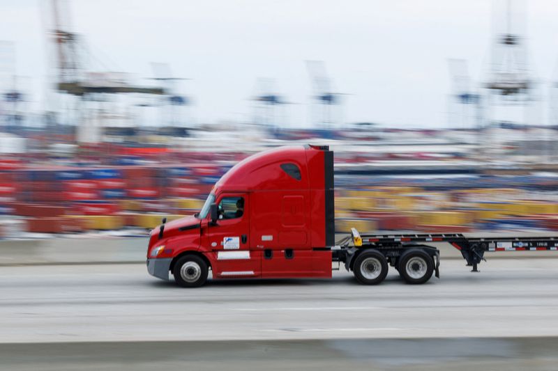 A semi-truck drives past shipping containers at the Port of Los Angeles in Wilmington, California, U.S., November 5, 2025. REUTERS/Mike Blake