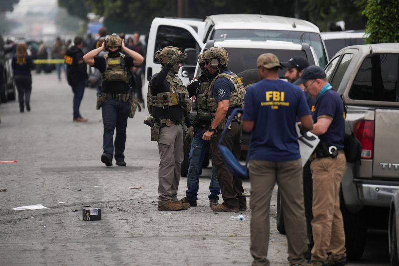 Federal agents, including the FBI, work at the scene where shots were fired during an immigration enforcement operation in the Los Angeles County city of Compton, California, U.S., January 21, 2026. REUTERS/Daniel Cole
