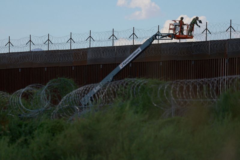 FILE PHOTO: U.S. Army combat engineers place razor wire on the U.S.-Mexico border wall to reinforce security in El Paso Texas, as seen from Ciudad Juarez, Mexico July 24, 2025. REUTERS/Jose Luis Gonzalez/File Photo