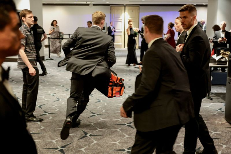 A security official runs with a bag as a shooter opens fire during the annual White House Correspondents' Association dinner in Washington, D.C., U.S., April 25, 2026. REUTERS/Jonathan Ernst