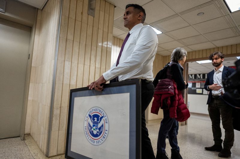 FILE PHOTO: A person carries a framed logo of U.S. Department of Homeland Security in the hallway of U.S. immigration court in Manhattan, in New York City, U.S., January 13, 2026. REUTERS/David 'Dee' Delgado/File Photo