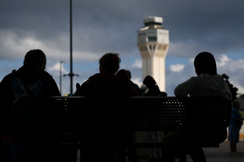 FILE PHOTO: Passengers sit on a bench, after flights were delayed and cancelled when the airspace was closed due to U.S. strikes on Venezuela overnight, at Luis Munoz Marin International Airport in Carolina, near San Juan, Puerto Rico January 3, 2026. REUTERS/Ricardo Arduengo/File Photo