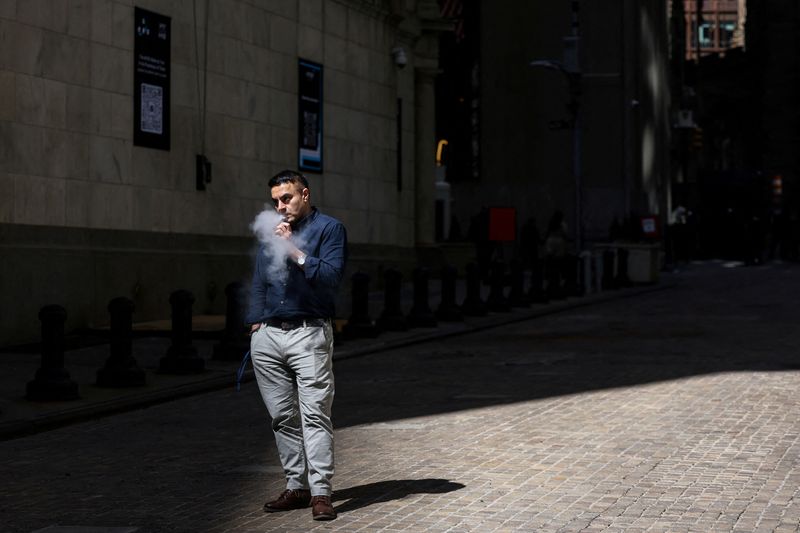 A man uses an e-cigarette on Wall Street outside the New York Stock Exchange (NYSE) in New York City, U.S., April 9, 2025. REUTERS/Kylie Cooper