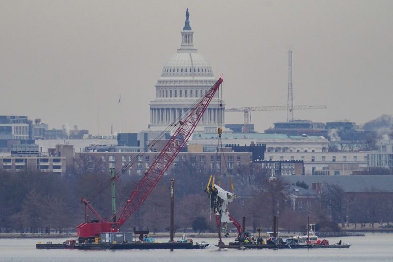 A crane retrieves part of the wreckage from the Potomac River, in the aftermath of the collision of American Eagle flight 5342 and a Black Hawk helicopter that crashed into the river, with the Capitol dome in the background, as seen from Virginia, U.S., February 3, 2025.REUTERS/Nathan Howard/File Photo