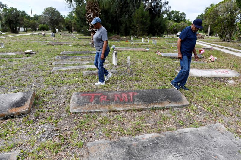Family members of those buried at the Old Memphis Cemetery, a predominantly African-American cemetery in Palmetto, walk near a tomb with the word "Trump" spray-painted on it as they inspect their loved ones’ graves, after 17 gravesites and several headstones were vandalized in Palmetto, Florida, U.S., May 14, 2026. Authorities say “Trump” and “DeSantis” were spray-painted in red across multiple tombs as police continue investigating the incident. REUTERS/Octavio Jones