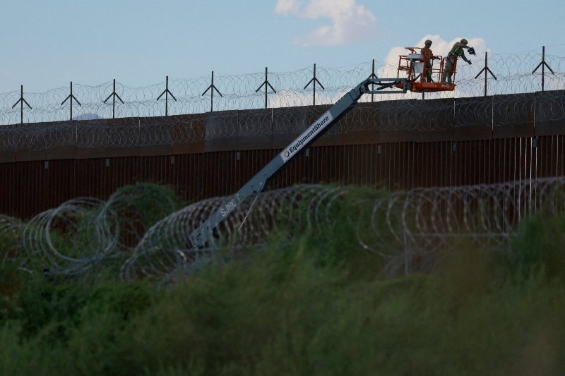 FILE PHOTO: U.S. Army combat engineers place razor wire on the U.S.-Mexico border wall to reinforce security in El Paso Texas, as seen from Ciudad Juarez, Mexico July 24, 2025. REUTERS/Jose Luis Gonzalez/File Photo