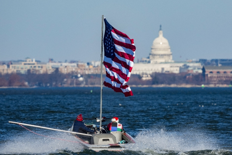 A boater flies an American flag on the Potomac River, with the U.S. Capitol visible in the background near Alexandria, Virginia, U.S., December 24, 2025. REUTERS/Ken Cedeno
