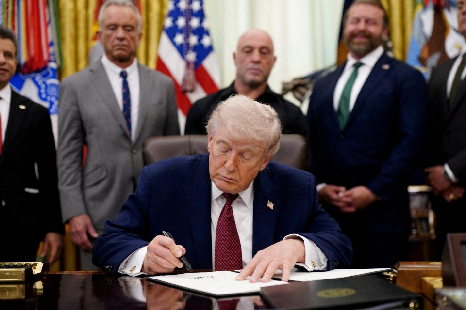 FILE PHOTO:  U.S. President Donald Trump signs an executive order encouraging more research into ibogaine, next to U.S. Health and Human Services (HHS) Secretary Robert F. Kennedy Jr., Joe Rogan, and Americans for Ibogaine CEO W. Bryan Hubbard, in the Oval Office of the White House in Washington, D.C., April 18, 2026. REUTERS/Nathan Howard/File Photo