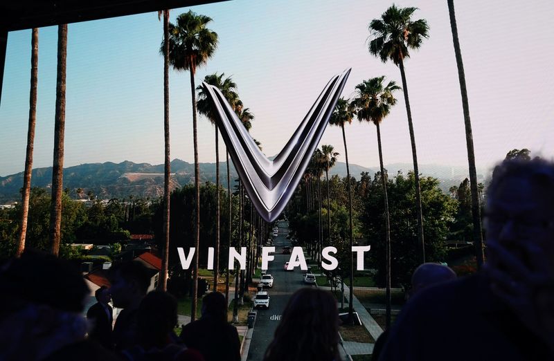 People walk next to a VinFast logo on a screen during the press day at the Los Angeles Auto Show in Los Angeles, California, U.S. November 17, 2022. REUTERS/Mike Blake