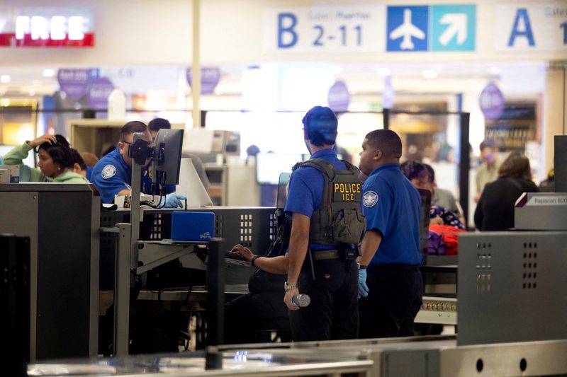 An Immigration and Customs Enforcement (ICE) agent assists Transportation Security Administration (TSA) officers as passengers are screened at a checkpoint at Luis Munoz Marin International Airport in Carolina, Puerto Rico, March 27, 2026. REUTERS/Ricardo Arduengo