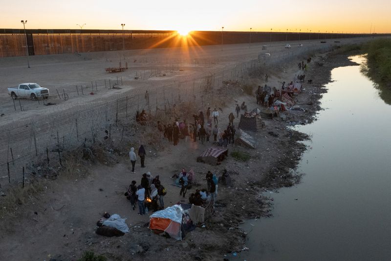 A drone view shows the sun rise over migrants as they stand along the U.S. side of the Rio Grande while the U.S. 5th Circuit Court of Appeals hears oral arguments on Texas' motion to lift a block on its SB4 immigration law that would allow state officials to arrest migrants suspected of being in the country illegally, in El Paso, Texas, U.S., March 22, 2024. REUTERS/Adrees Latif