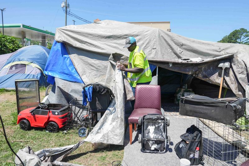 Benjamin Brown, 54, who is currently experiencing homelessness, opens up the tarps to show the inside of his tent in Atlanta, Georgia, U.S., May 15, 2026.   REUTERS/Megan Varner