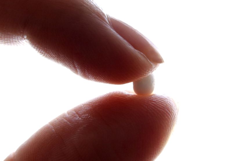 An illustration picture shows a woman holding a pill. REUTERS/Eric Gaillard