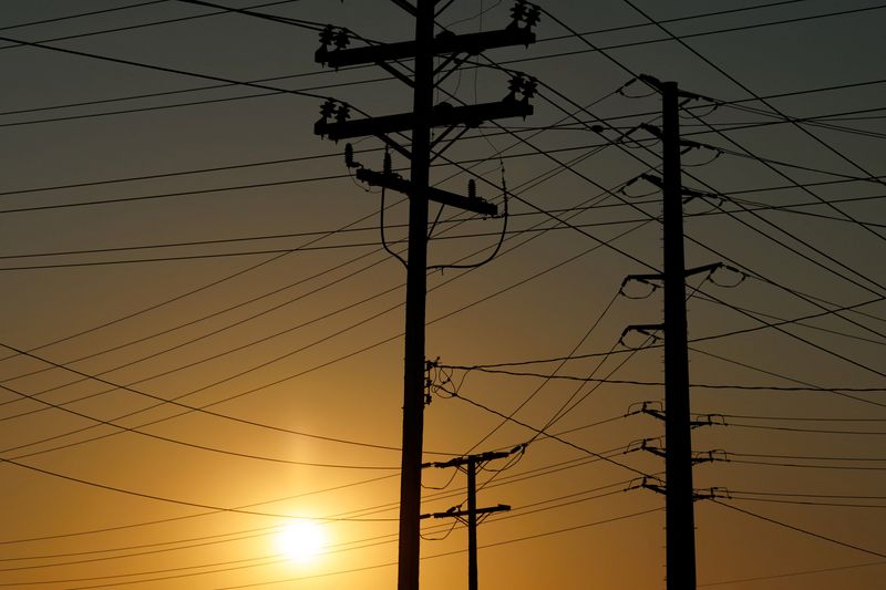 Electrical transmission poles and lines are shown in the early morning of a hot summer day in Commerce, California, U.S, August 7, 2025.  REUTERS/Mike Blake
